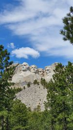 Low angle view of trees against cloudy sky, mount rushmore