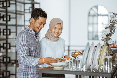 Smiling friends using mobile phone in restaurant