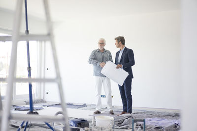 Man in suit and senior man talking on room under construction