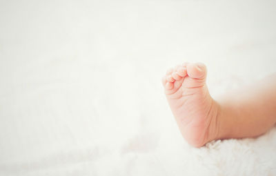 Low section of baby lying on bed