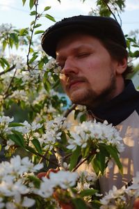 Portrait of young man looking at flowering plant