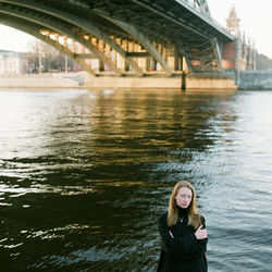 A woman stands at sunset near the bridge