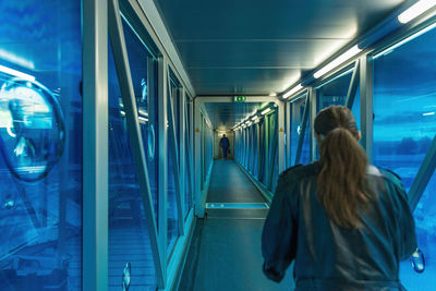 Rear view of women walking in illuminated train