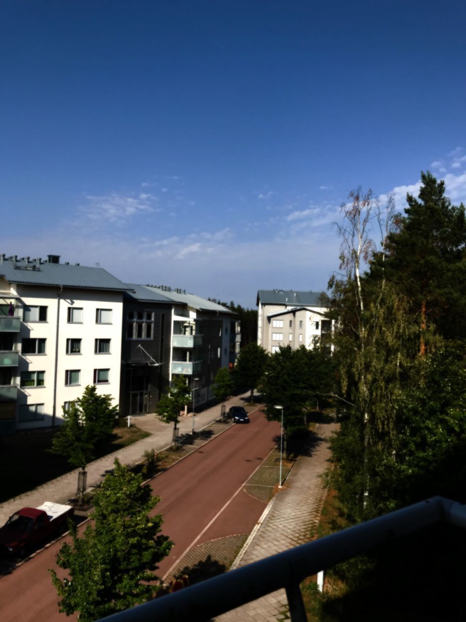 ROAD AMIDST BUILDINGS AGAINST BLUE SKY