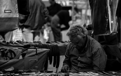 Mature man selling belt at market stall