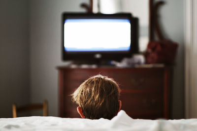 Rear view of boy watching television at home