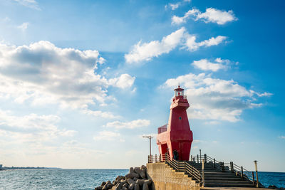 Lighthouse by sea against sky