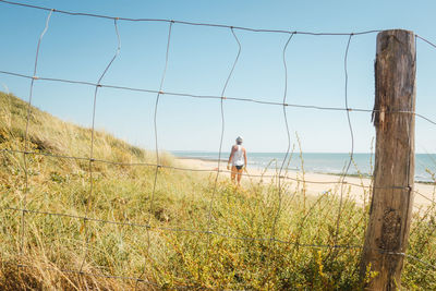 Man standing on shore by sea against sky