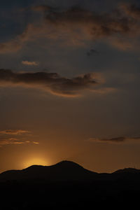 Low angle view of silhouette mountain against dramatic sky