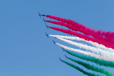 Low angle view of airplanes flying against blue sky