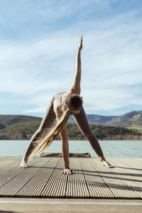 Active woman doing triangle pose on jetty