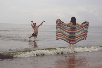 Couple enjoying in sea against sky