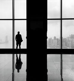 Silhouette man looking through window in building