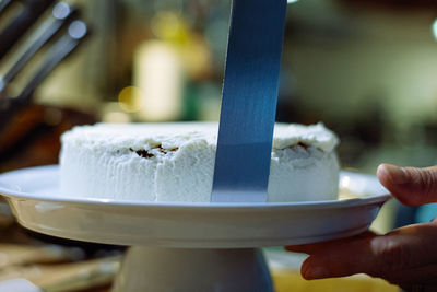 Person prepairing cake with whipped cream on table