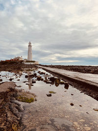 Lighthouse by sea against sky