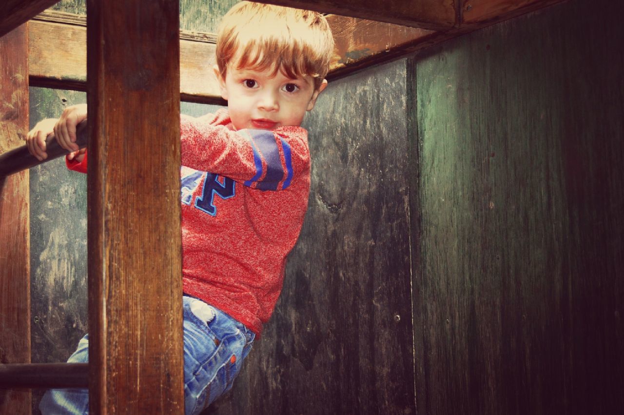 BOY STANDING ON WOODEN FLOOR IN ROOM