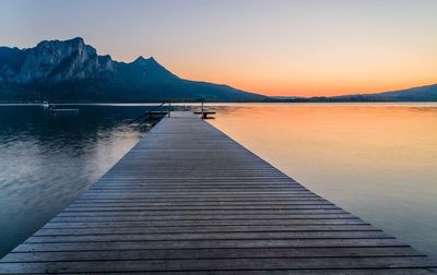 Pier over lake against sky during sunset