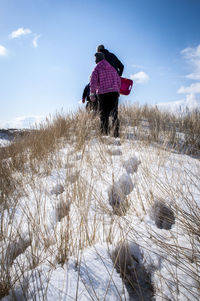 Rear view of people walking on snow covered field