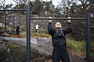 Young woman doing chin-ups exercise at outdoor gym