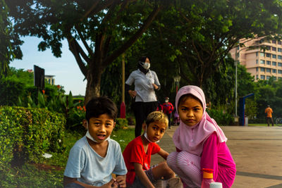 Portrait of cute kids sitting outdoors