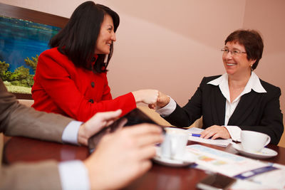 Smiling business colleagues discussing while sitting on table 