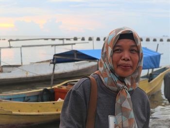 Portrait of smiling young woman standing on boat against sky