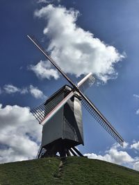 Low angle view of traditional windmill on field against sky