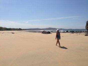 Woman walking on sand against sea at beach