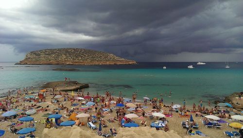 High angle view of crowd at beach against cloudy sky