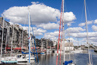 Sailboats in harbor against sky