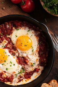 Breakfast with shakshouka and vegetables on a wooden table close up image