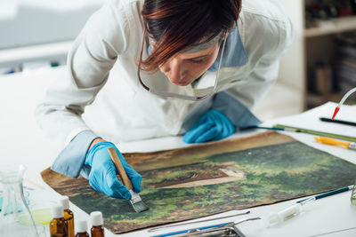 Restoring old oil painting, conservator removing varnish from an oil painting