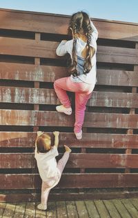 Rear view of siblings climbing on wooden wall