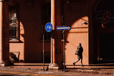 Side view of man walking against illuminated building