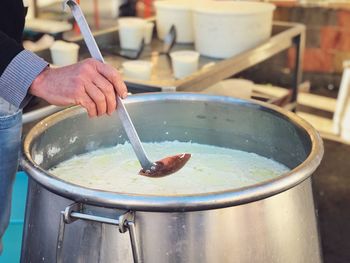 Midsection of person holding ladle over food in container