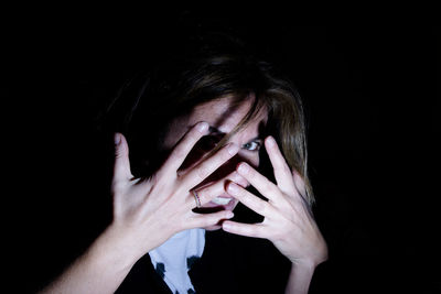 Portrait of woman covering her face with hands in darkroom