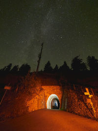 Road tunnel amidst trees against clear sky at night