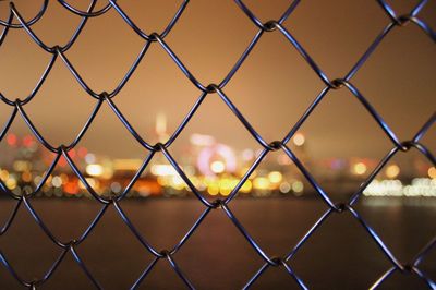 Full frame shot of chainlink fence against sky during sunset