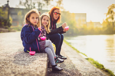 Family having ice cream while sitting at riverbank