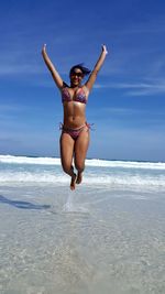 Full length of woman jumping over sea against sky