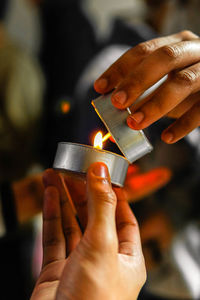 Cropped hands of people lighting candles