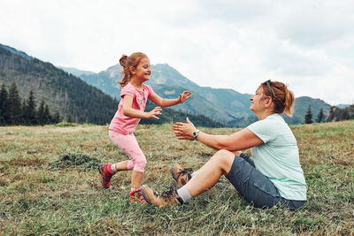 Little girl playing with her mother on grass enjoying summer day. happy family playing in the field