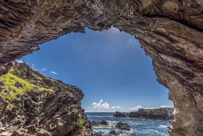 Rock formations by sea against blue sky