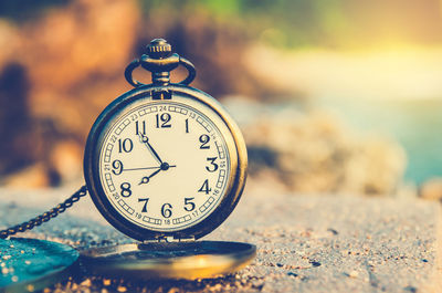 Close-up of clock on sand at beach