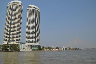 Modern buildings by sea against clear sky