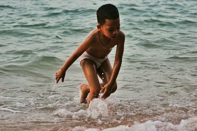 Full length of shirtless boy on beach