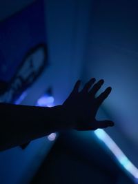 Close-up of silhouette hand on illuminated light