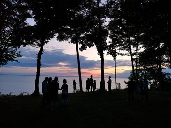 Silhouette people standing on field against sky during sunset