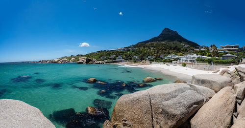 Panoramic view of sea and rocks against blue sky