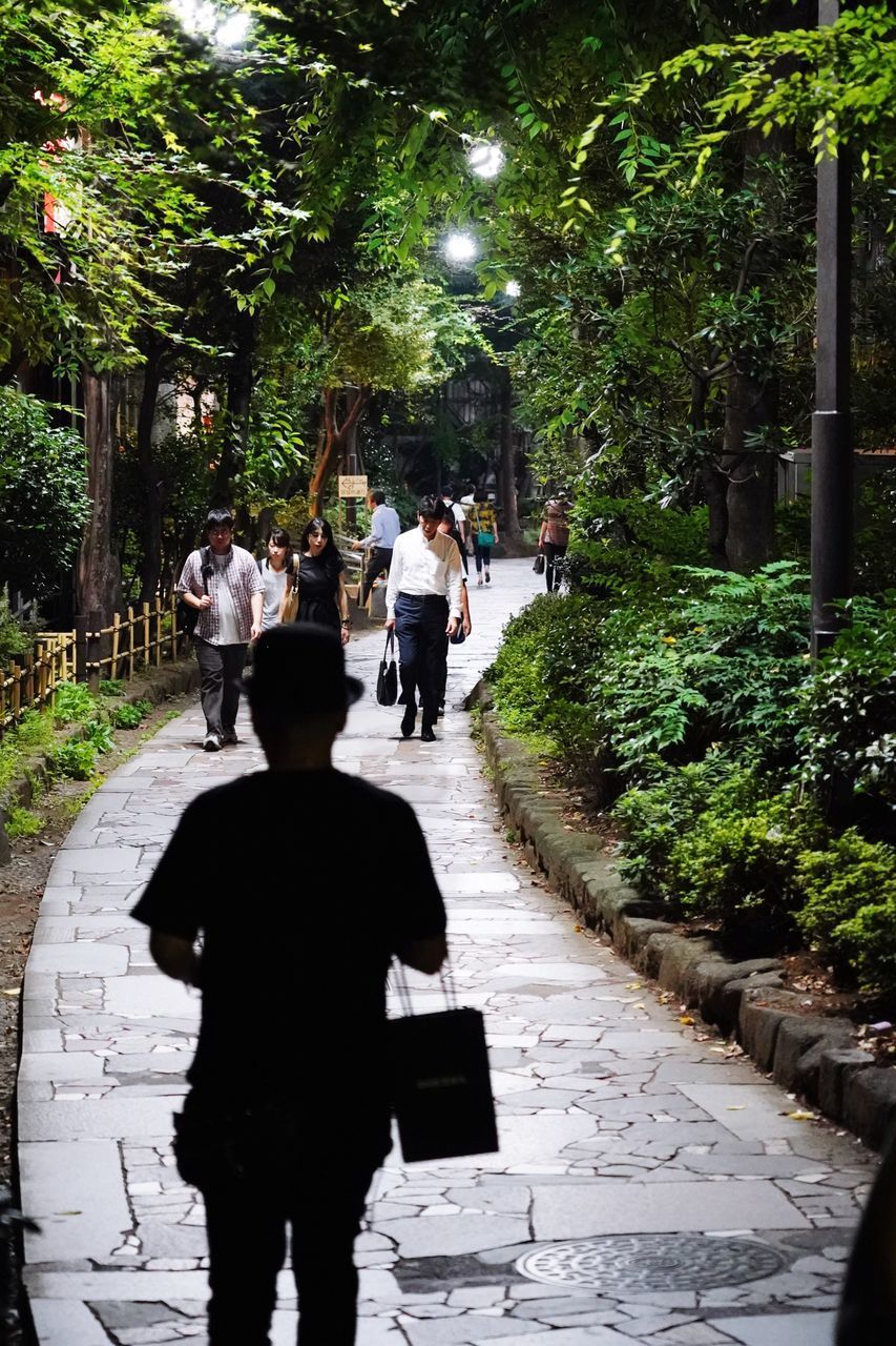 REAR VIEW OF PEOPLE WALKING ON STREET IN CITY